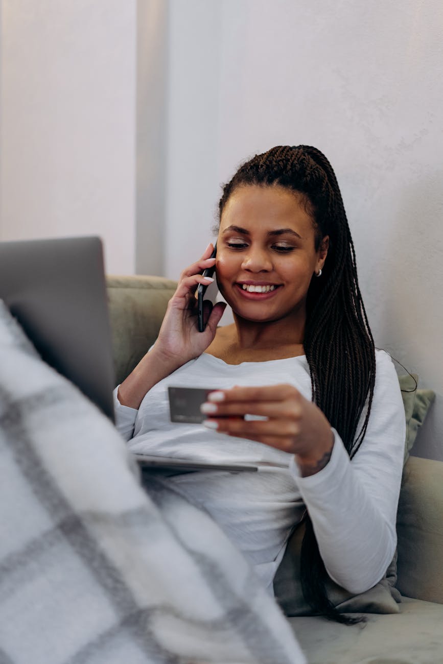 woman holding smartphone to her ear while looking at the credit card
